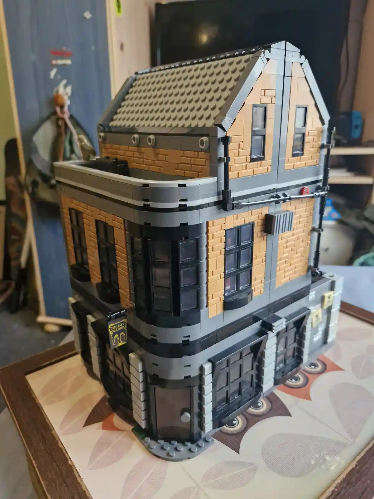 A detailed LEGO model of The Leaky Cauldron pub from Harry Potter, constructed with tan brick pieces, black windows, and…