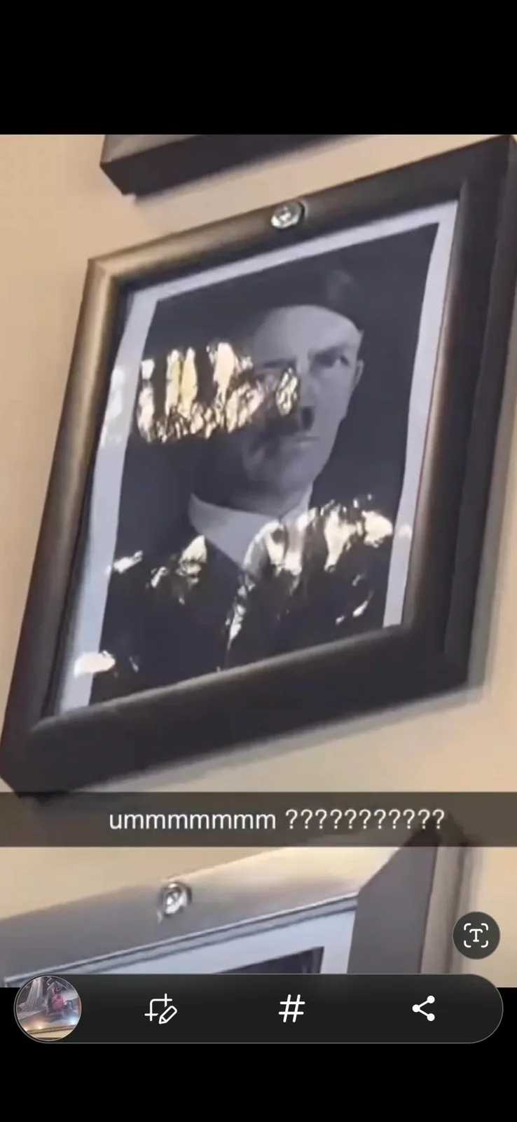A framed black-and-white portrait of a man with a mustache, likely Adolf Hitler, is mounted on a wall. The portrait's face…