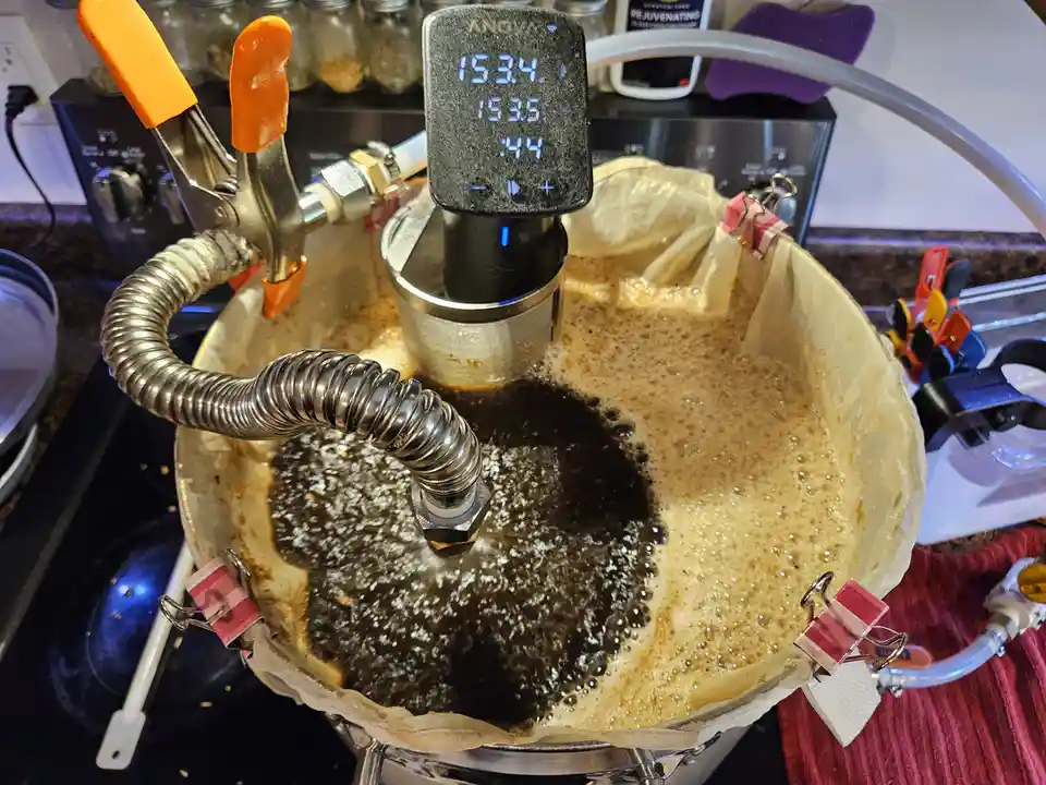 A close-up photo shows a brewing setup with a digital thermometer displaying '153.4', '153.5', and ':44'. The liquid in the…