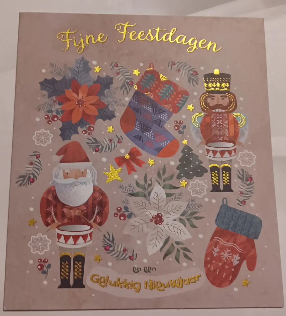 A festive holiday greeting card features illustrations of a Santa Claus and a nutcracker soldier, both holding drums…