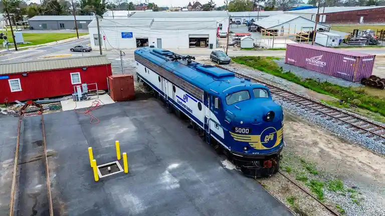 An aerial photo shows a blue and white CPR (CancerParrot Railnet) locomotive, numbered 5000, parked on tracks next to a…