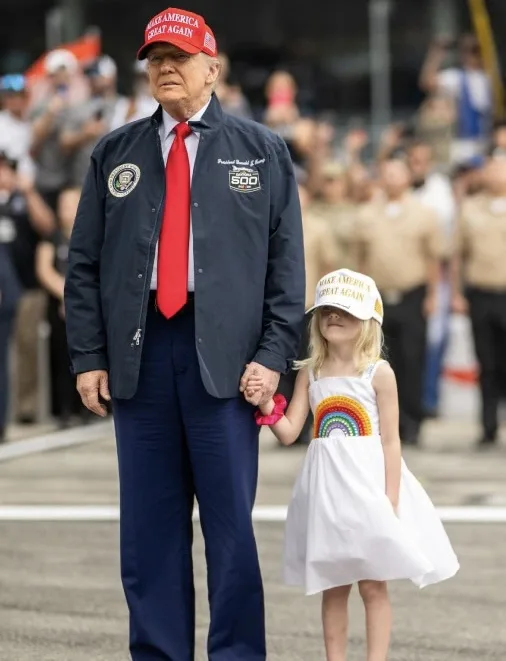 Former president Donald Trump walks hand-in-hand with a young girl wearing a matching 'MAKE AMERICA GREAT AGAIN' cap and a…