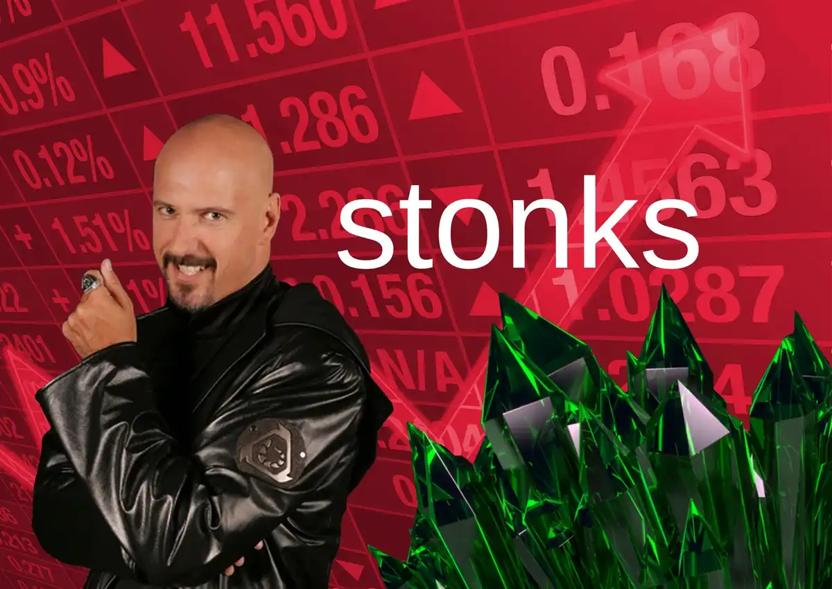 A bald man in a black leather jacket with a mustache, smiling and holding up a finger, stands before a red stock ticker…
