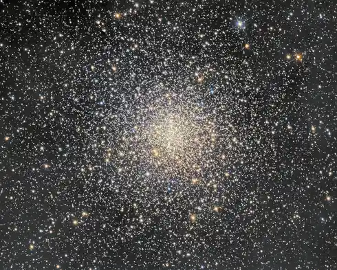 A dense, spherical star cluster with countless stars radiating outward from a bright center against a dark background…