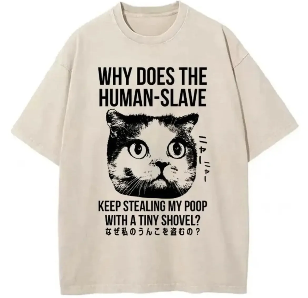 A beige t-shirt displays a black-and-white illustration of a cat's face with wide, surprised eyes. Above the cat, bold text…