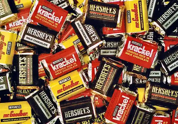 A dense pile of various Hershey's chocolate bars, including Krackel, Special Dark, and Mr. Goodbar, with their colorful…