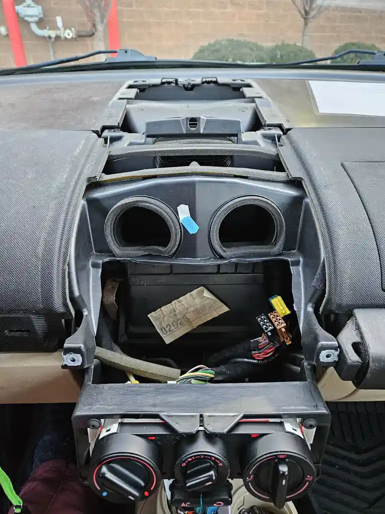 The image shows the interior of a car with the dashboard center console completely disassembled, exposing wiring…