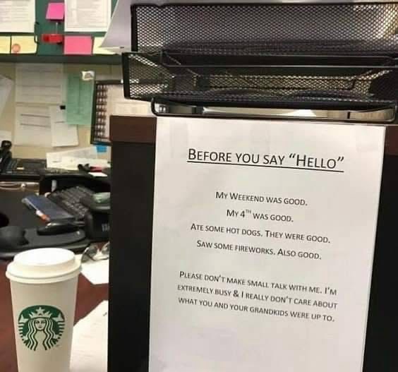 A printed sign taped to an office cubicle door reads 'BEFORE YOU SAY HELLO' followed by a humorous list of weekend…
