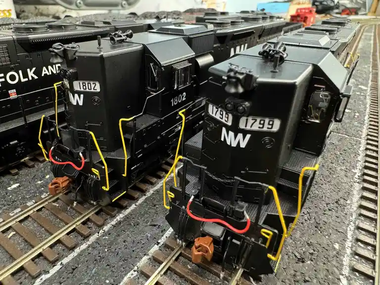 Two black model trains with 'NW' logos and numbers 1802 and 1799 sit on adjacent tracks, with the number 1799 overlaid as…