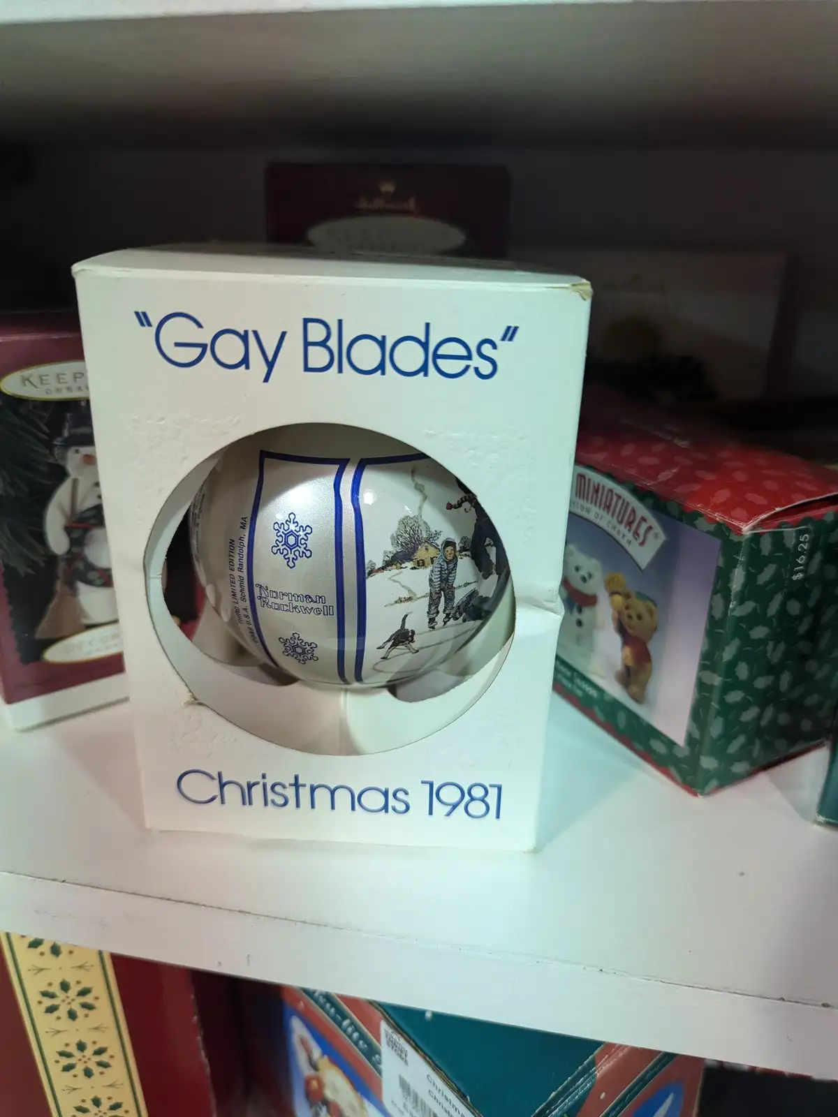 A 1981 Norman Rockwell Christmas ornament in its original box, which has been humorously edited to read 'Gay Blades' instead…