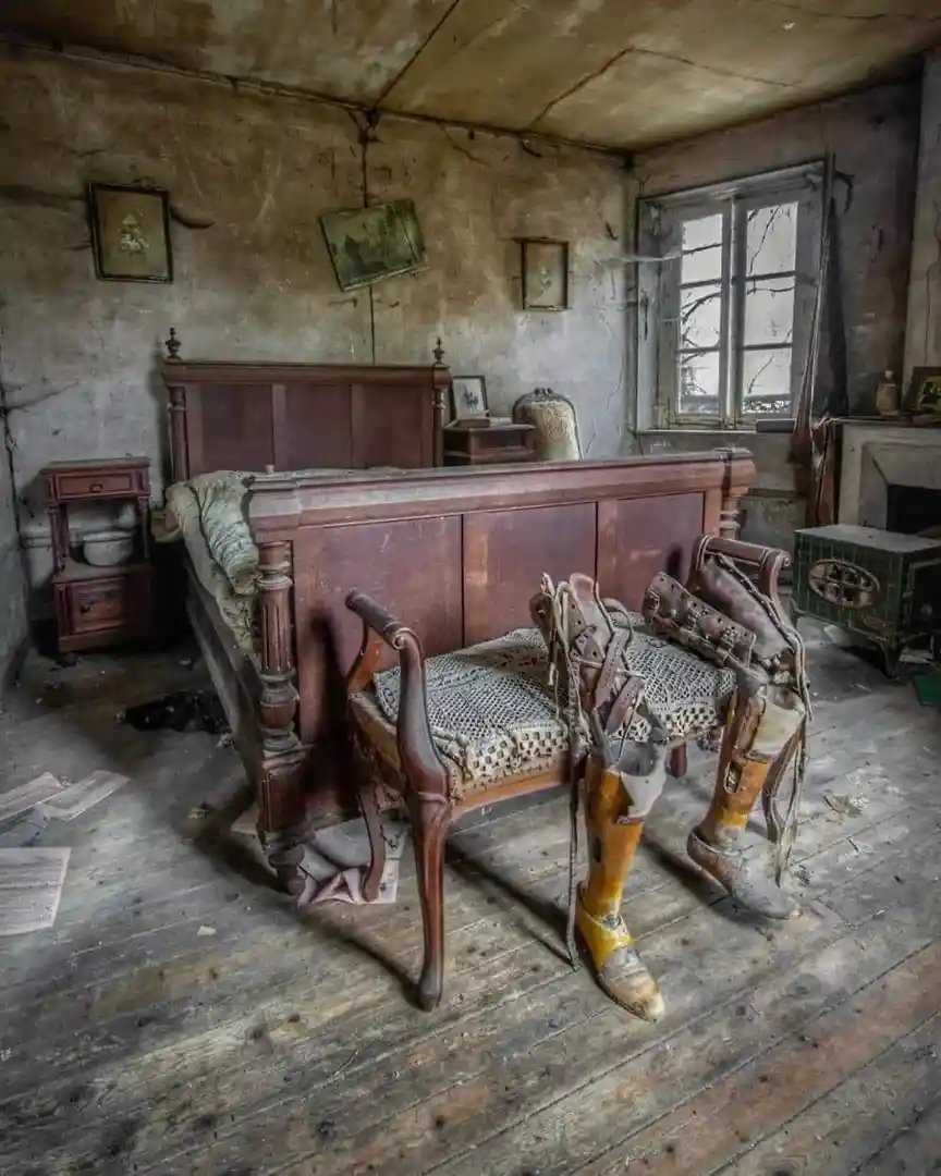 An abandoned, dilapidated room with peeling walls and old furniture, featuring a wooden chair with a crocheted seat cover…