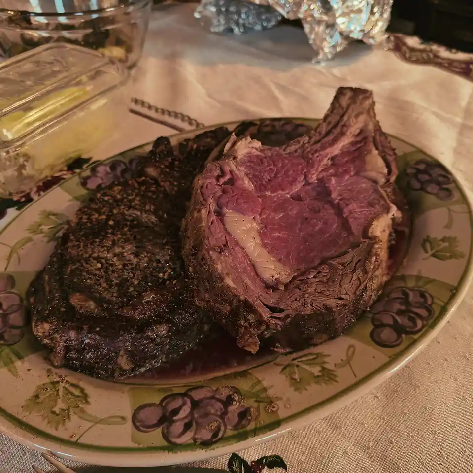 A close-up photo shows a plate with two pieces of cooked beef: one is a thick, sliced roast with a pink center and charred…