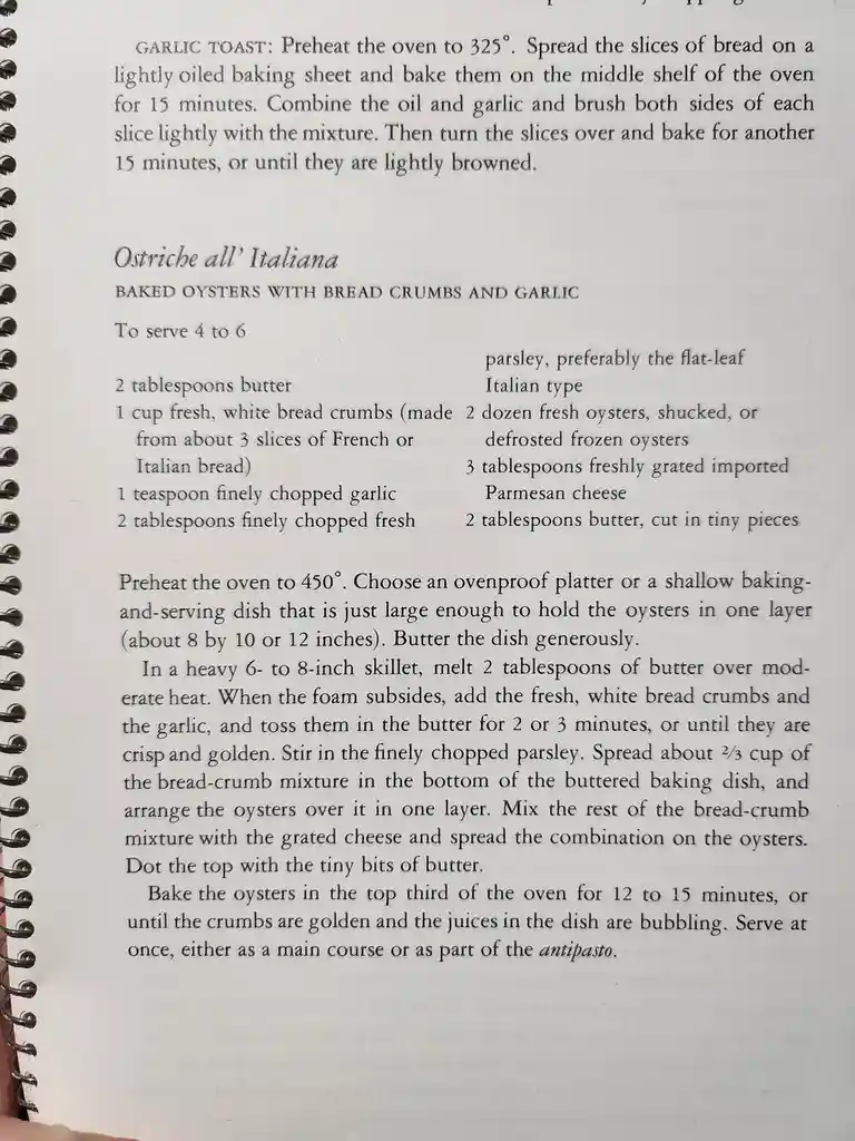 A close-up photo of a spiral-bound cookbook page showing a recipe titled 'Ostriche all' Italiana' (Baked Oysters with Bread…