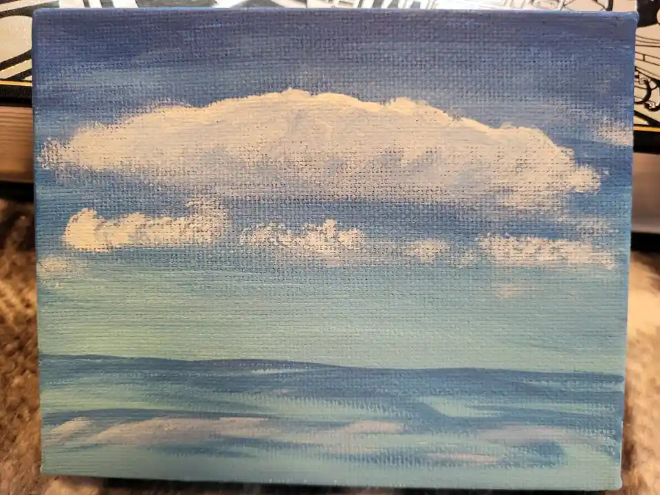 A hand-painted canvas depicts a serene sky with clouds over a calm sea, rendered in textured blue and white paint. The…