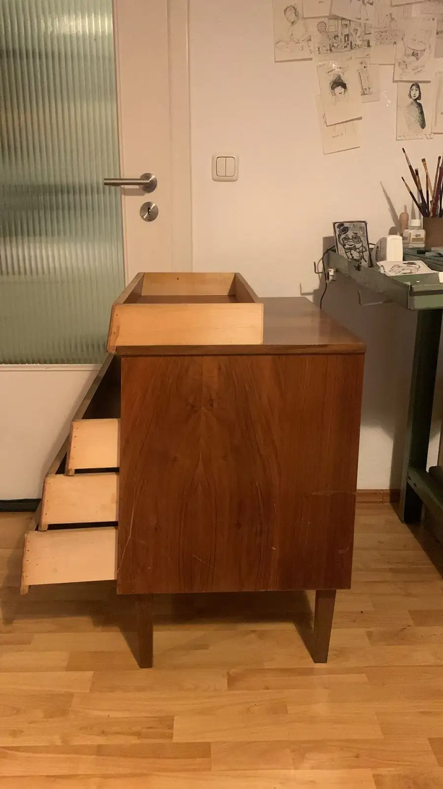 A wooden desk with a built-in wooden basin on top and three visible wooden steps descending from its left side, placed in a…