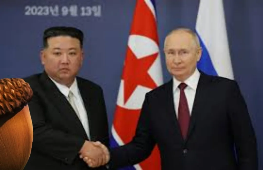 Two men in suits shake hands in front of North Korean and Russian flags, with a large acorn graphic superimposed over the…