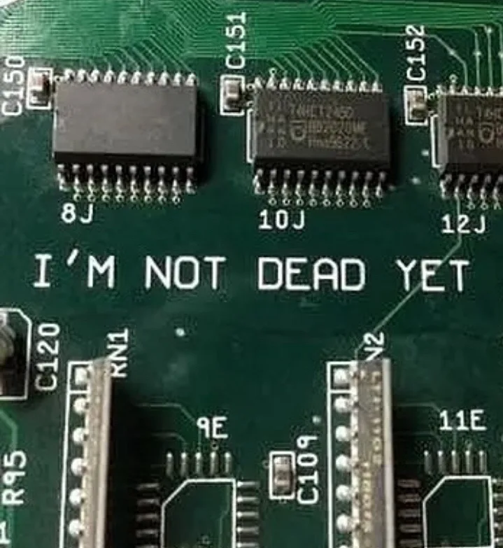 A close-up photo of a green circuit board with several black integrated circuits and labeled components. White text overlaid…
