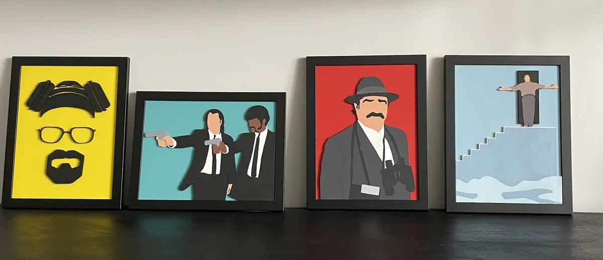 Four framed paper-cut art pieces depict characters from TV shows: a yellow-framed portrait of Walter White with his…