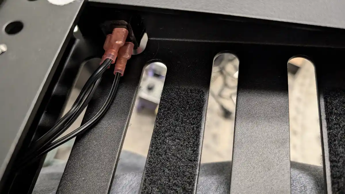A close-up photo shows two black wires with translucent reddish-brown connectors plugged into a black plastic housing inside…