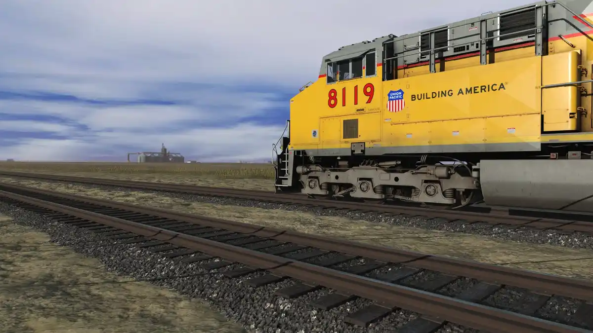 A yellow Union Pacific locomotive, numbered 8119 and bearing the slogan 'Building America', is shown on a rural railroad…