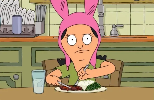 A cartoon woman wearing a pink bunny hat sits at a kitchen table, looking annoyed while cutting into a steak with a knife…