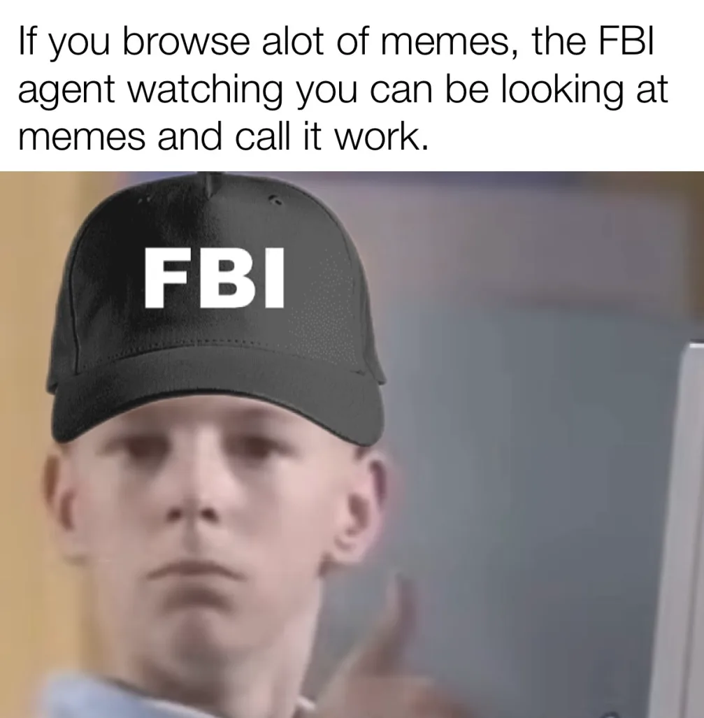 A blurry image of a man wearing a black baseball cap with 'FBI' written in white letters on the front. He is looking at a…