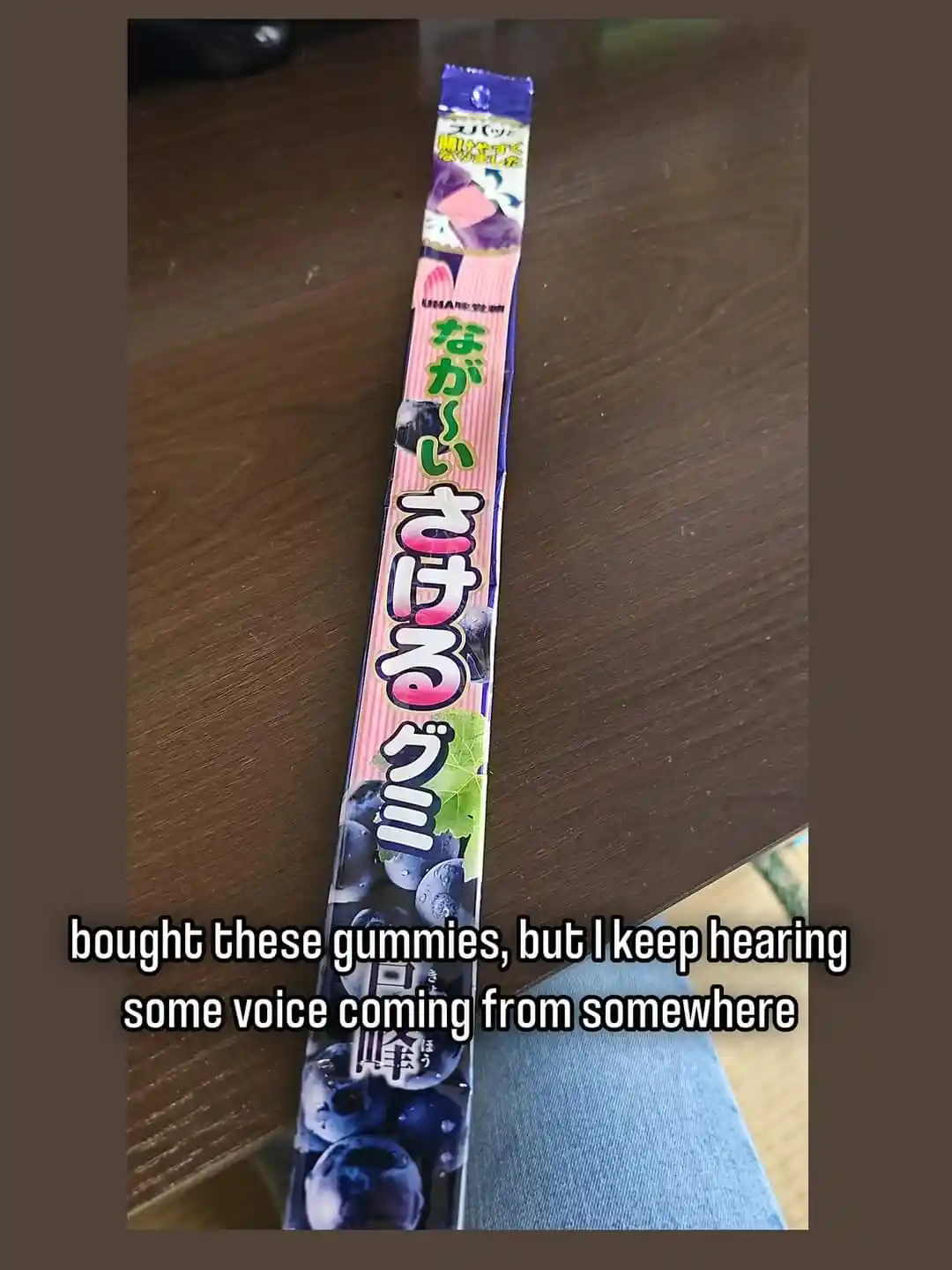 A long, thin package of Japanese blueberry-flavored gummy candies lies on a wooden table. The packaging features Japanese…