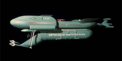 A gray, retro-futuristic spaceship with a cylindrical body and wing-like structures, labeled 'UNITED GALAXY SANITATION…