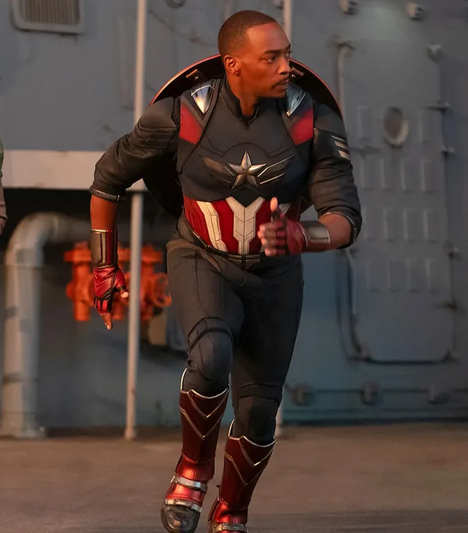 A man in a dark blue, red, and white superhero costume with a star emblem on the chest and a circular shield on his back is…
