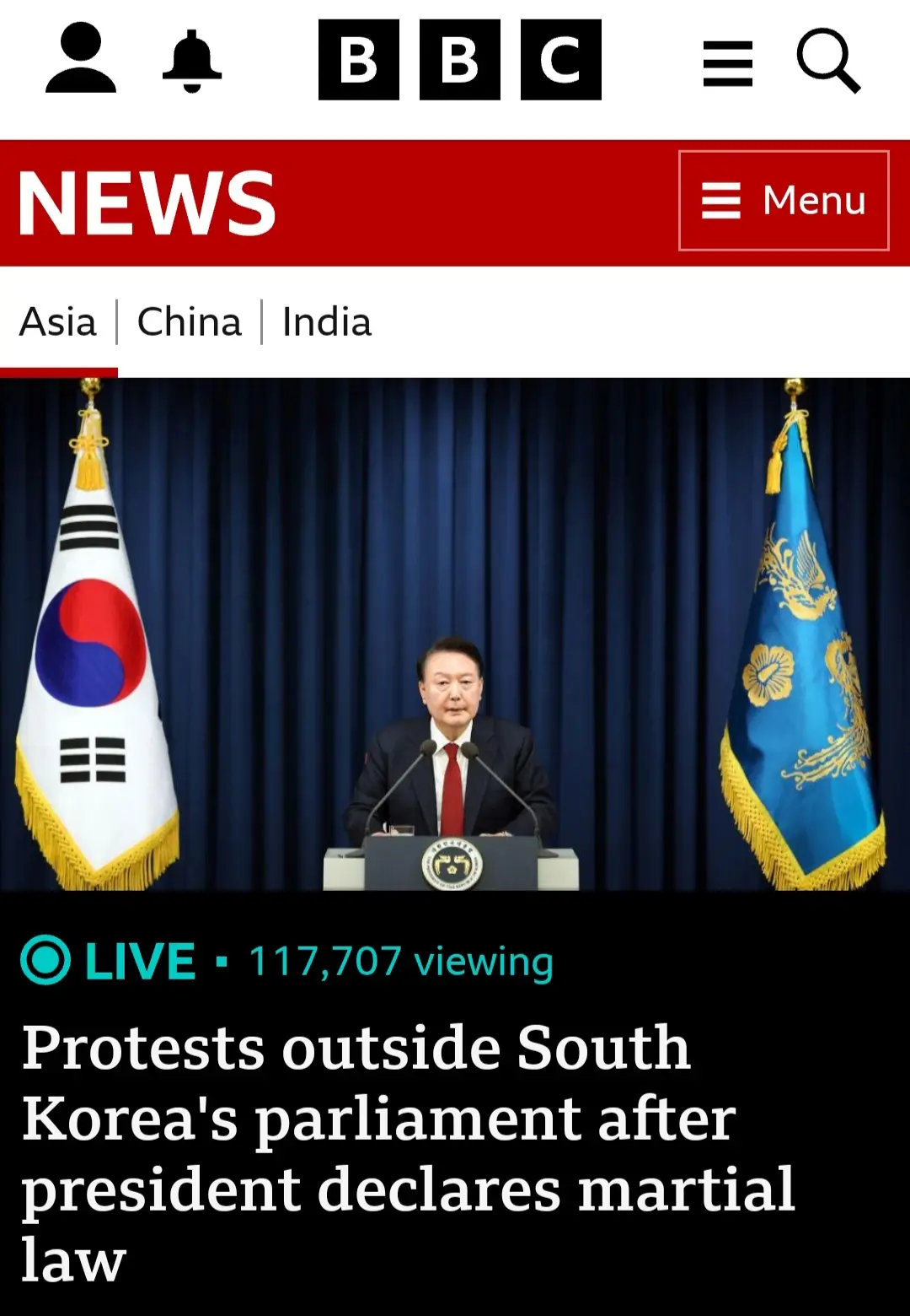 A screenshot of a BBC News article shows South Korean President Yoon Suk Yeol speaking at a podium flanked by the South…