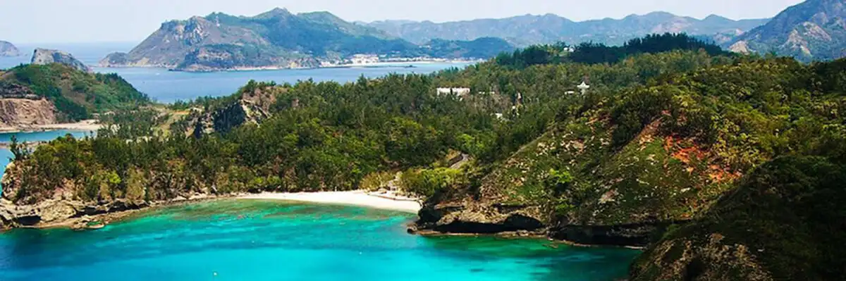 a panoramic view of a stunning tropical bay with turquoise water, a white sandy beach nestled between lush green hills, and…