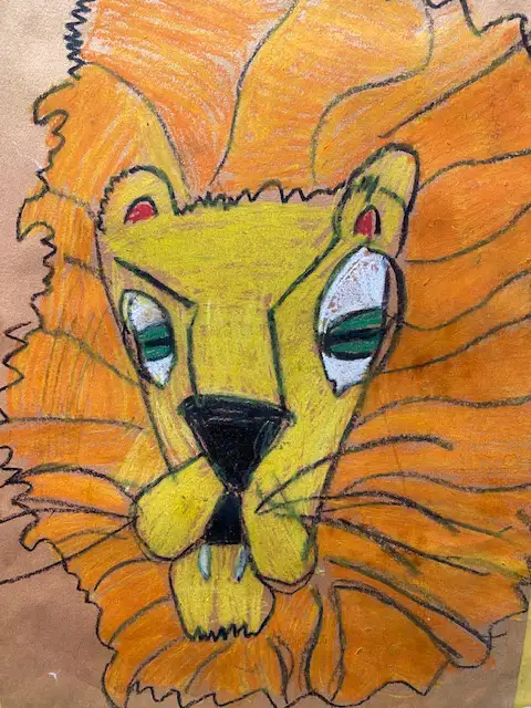 A child's crayon drawing of a lion's head with a yellow face, orange mane, and green eyes, overlaid with the text 'i'm not a…