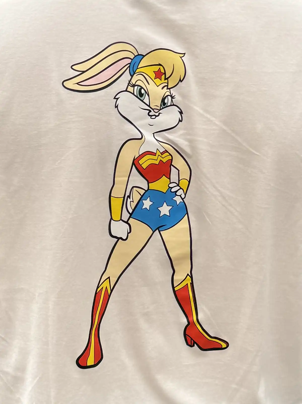 A white t-shirt displays a cartoon illustration of Bugs Bunny dressed in Wonder Woman's iconic costume, featuring a red and…