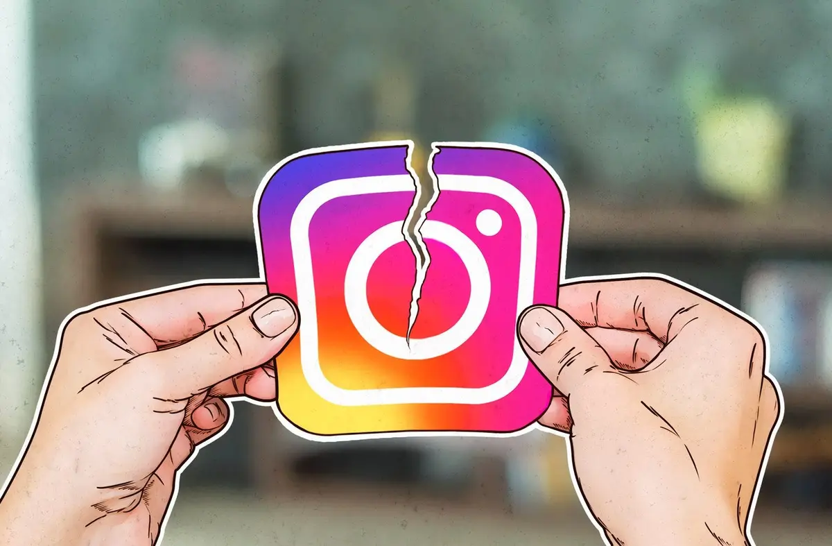 Two hands are shown tearing apart a sticker of the Instagram logo, which is visibly cracked down the middle. The background…