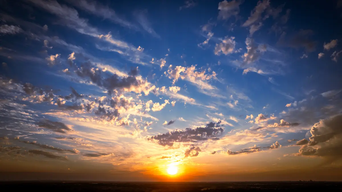 A wide-angle photograph captures a vibrant sunset with the sun low on the horizon, casting golden-orange light across…