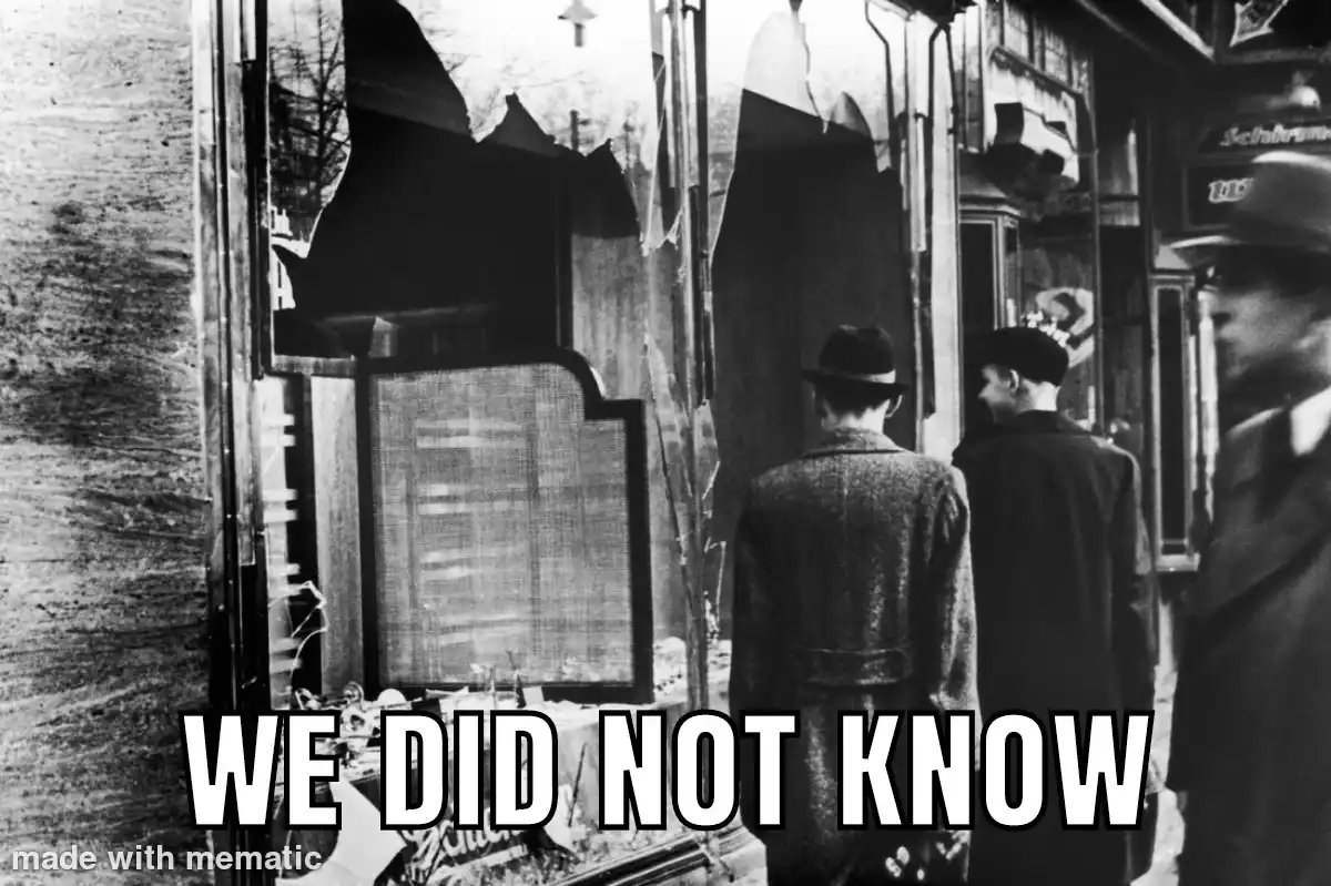 A black and white historical photo shows several men in coats and hats looking at a shattered storefront window with broken…