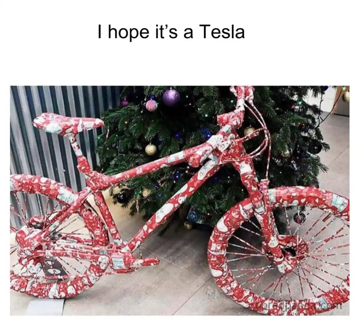 A bicycle is completely wrapped in red and white Christmas wrapping paper with cartoon characters, standing next to a…