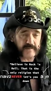 A man with a long beard and mustache wearing a black cowboy hat with a gold emblem looks directly at the camera. The image…