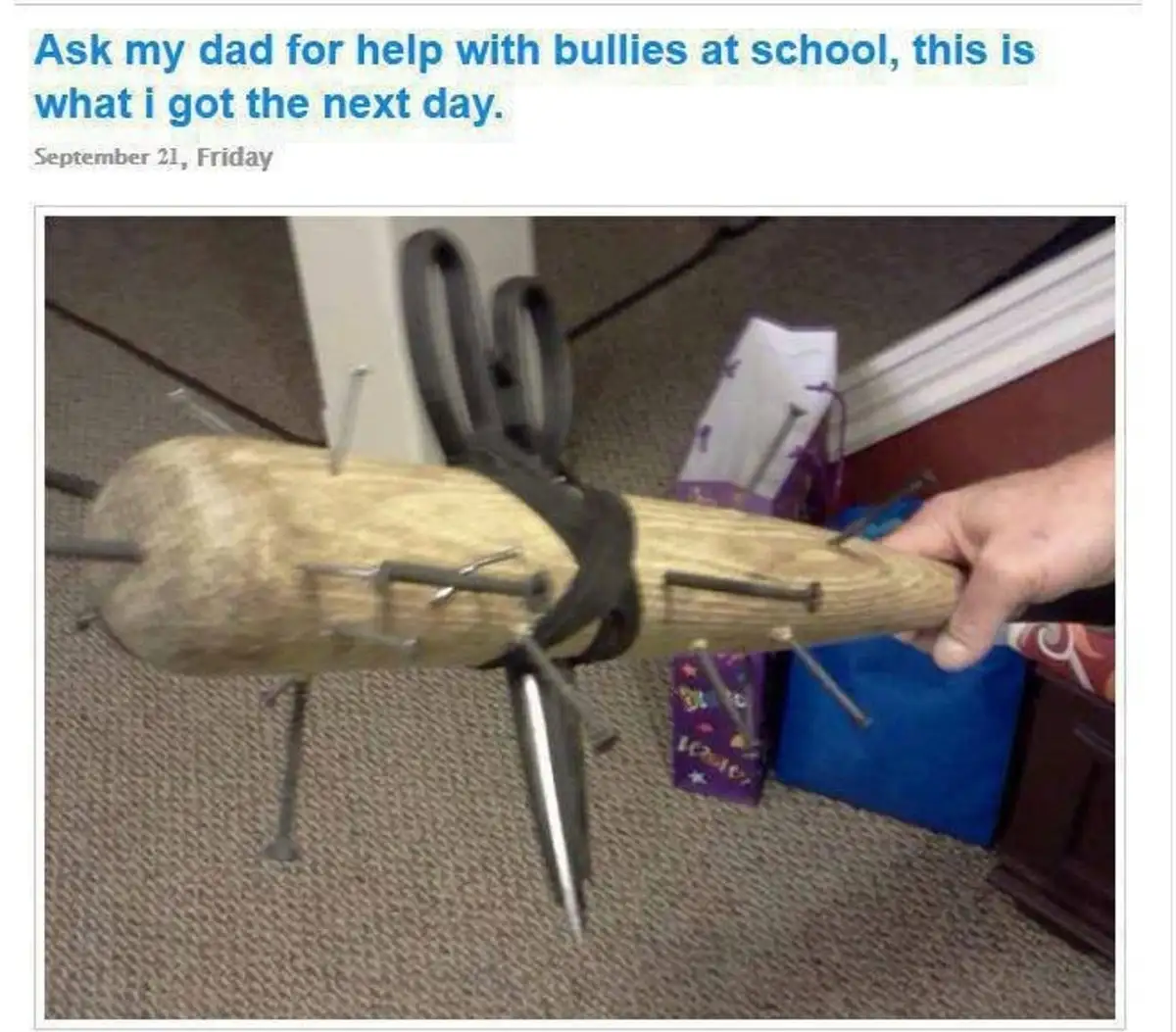A hand holds a wooden baton-like object embedded with numerous nails and a large pair of scissors strapped to it. The image…