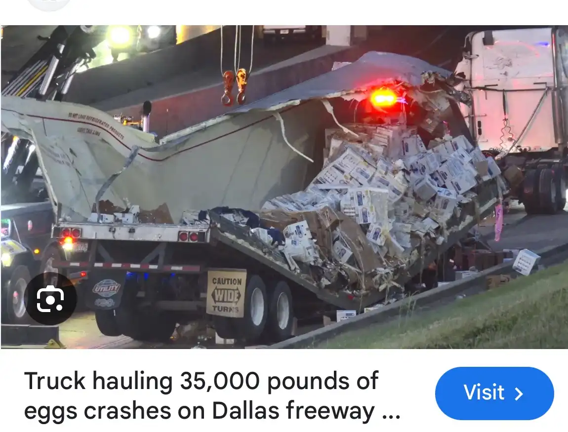 A damaged semi-truck trailer is shown overturned on a highway at night, its cargo of cardboard egg cartons spilled and…