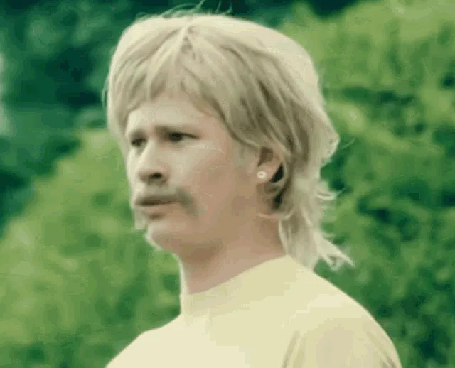 A six-panel image shows a man with blonde mullet hair, a mustache, and an earring, wearing a yellow shirt against a green…
