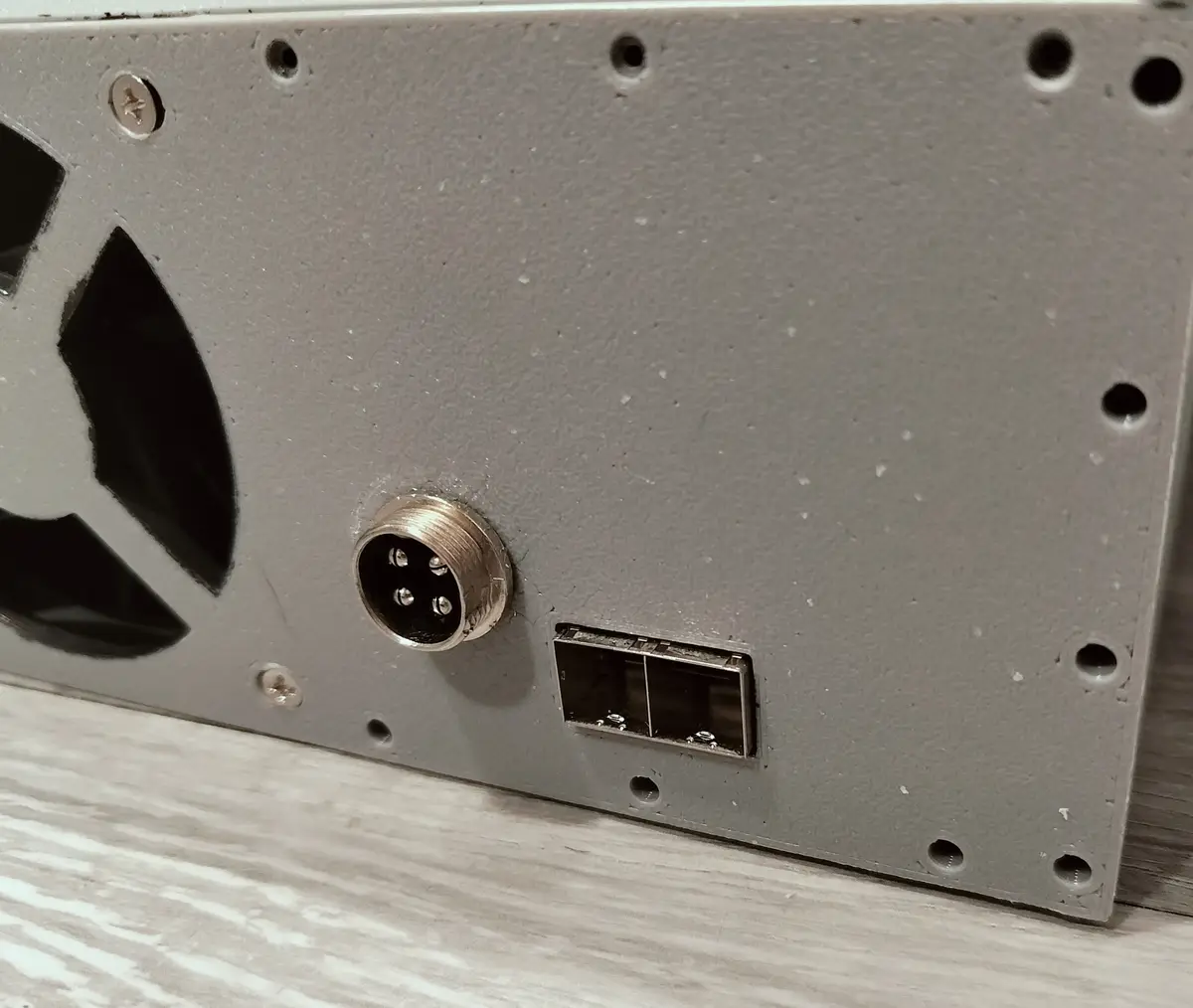 A close-up photo shows the back of a gray computer power supply unit with a circular 4-pin molex-style connector and a USB…