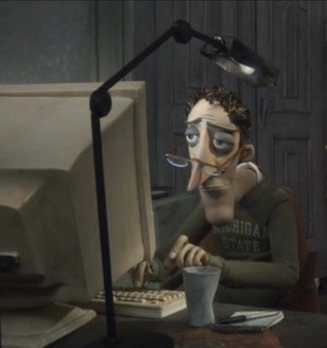 An animated man with tired eyes and glasses hanging from his nose sits at a desk with an old computer, keyboard, and lamp…
