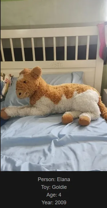 A large, fluffy brown and white stuffed cow toy named Goldie is lying on a bed with light blue sheets and a white headboard…