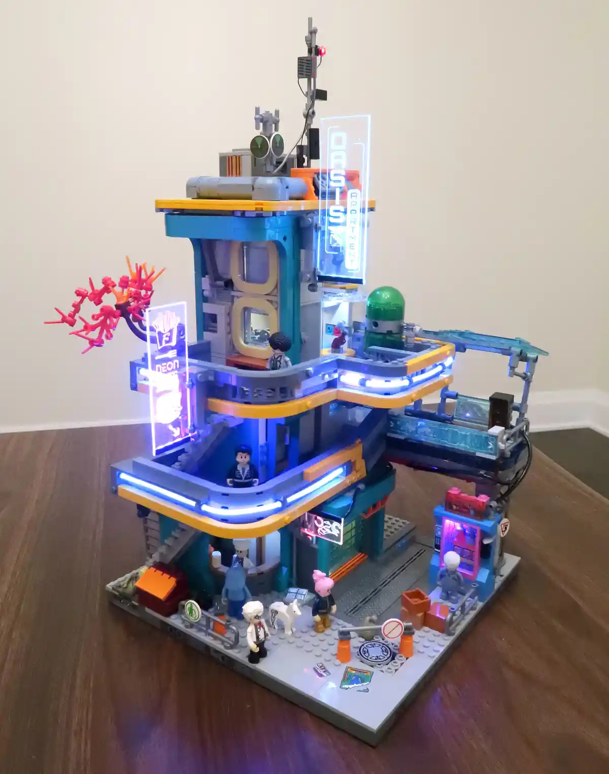 A detailed, multi-level LEGO model of a futuristic building with glowing blue and orange lights, featuring several LEGO…