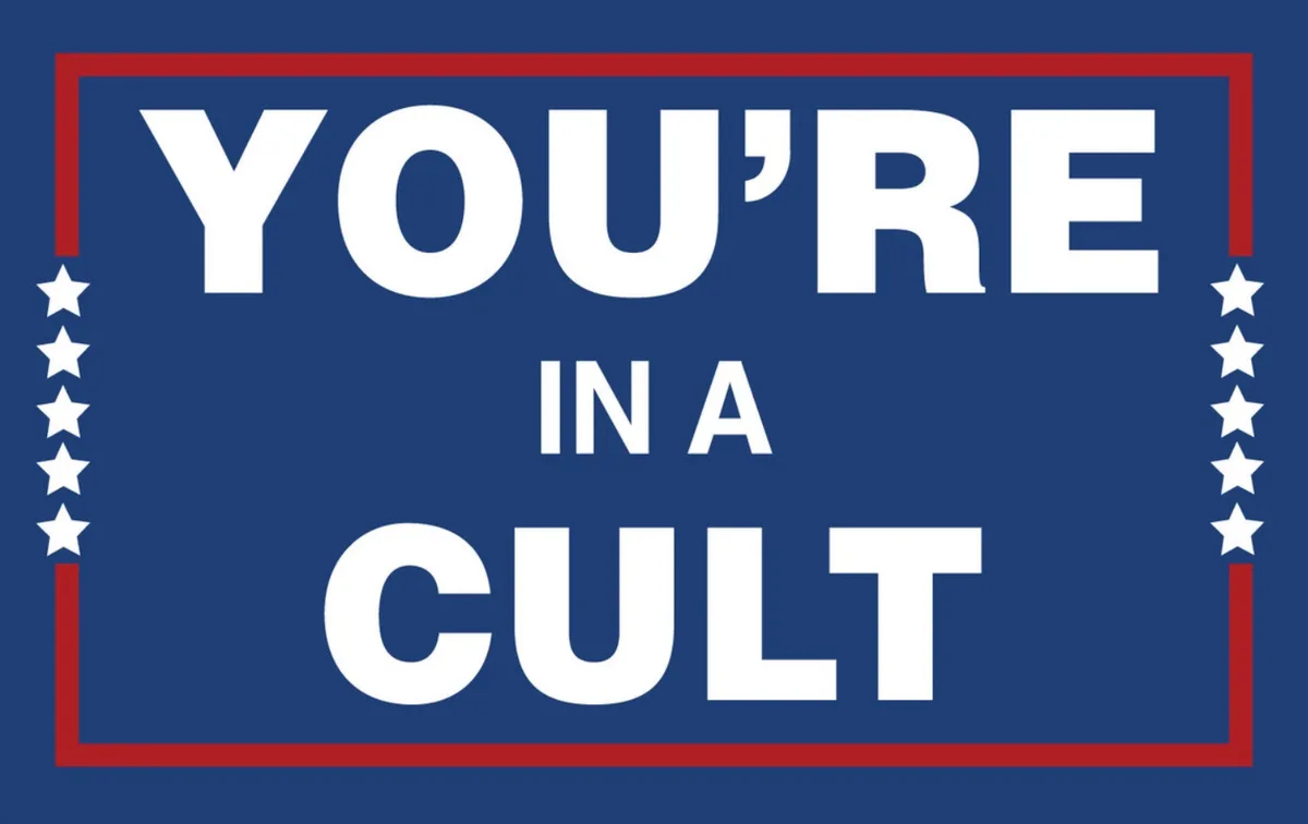 A blue sign with a red border and white stars on the sides displays the text 'YOU'RE IN A CULT' in large white capital…