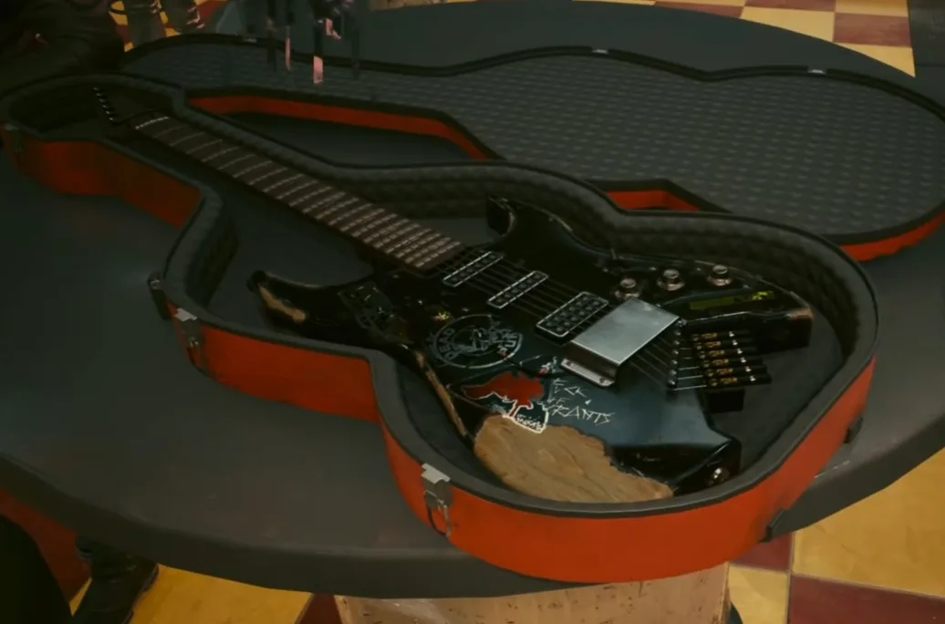 A black electric guitar with a large, irregularly shaped wooden patch on its body sits inside an open, red and black guitar…