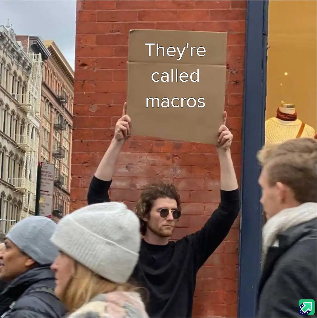 A man with curly hair and sunglasses holds up a cardboard sign that reads 'They're called macros' while standing on a city…