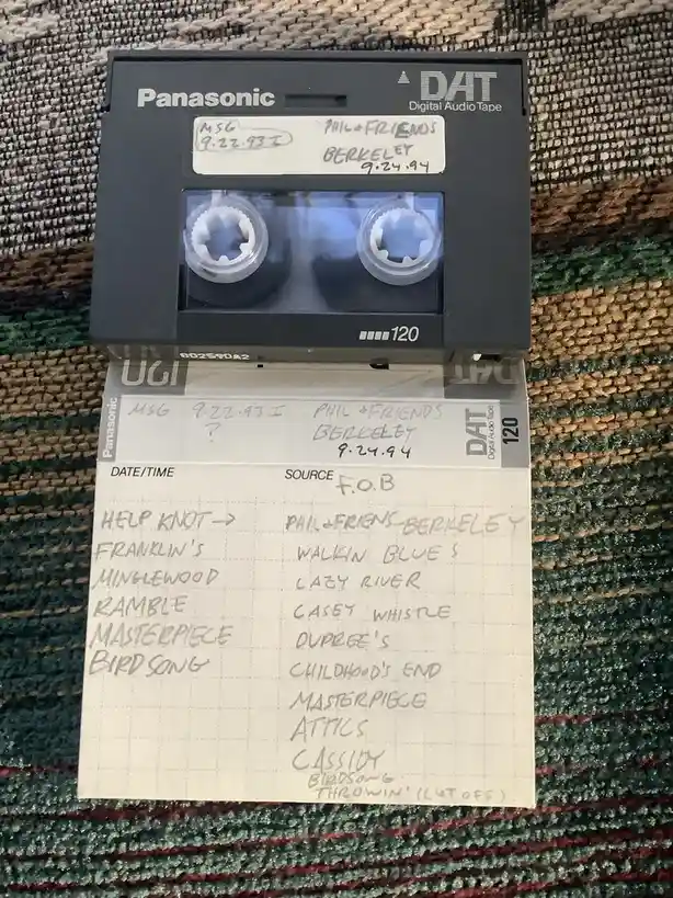 A Panasonic DAT tape and its accompanying handwritten log sheet, both labeled 'PHIL + FRIENDS BERKELEY 9.24.94'. The log…