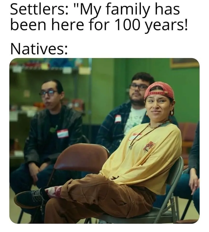 A meme image shows a woman in a yellow shirt and red cap sitting in a folding chair, looking smugly at the camera while two…